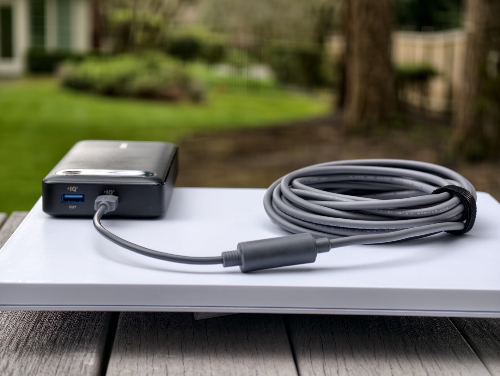 Flat lay of a Starlink Mini connected to a power source through a short adapter section and coiled cable.